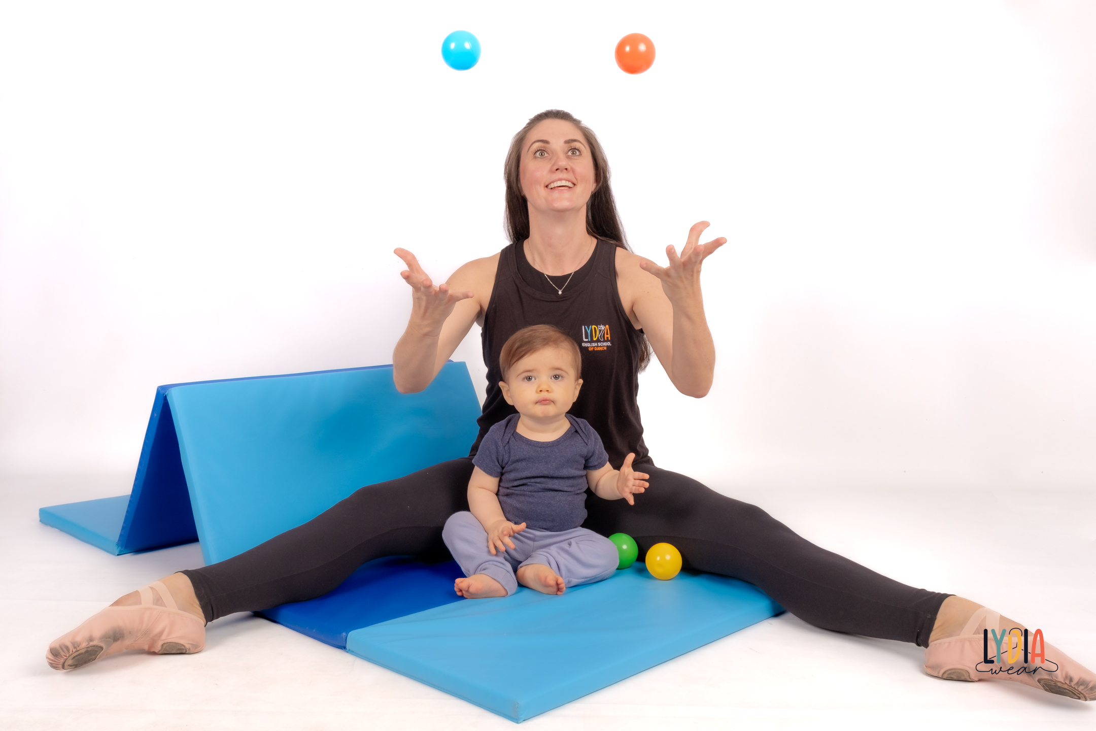Dance teacher juggling while seated with a baby in class